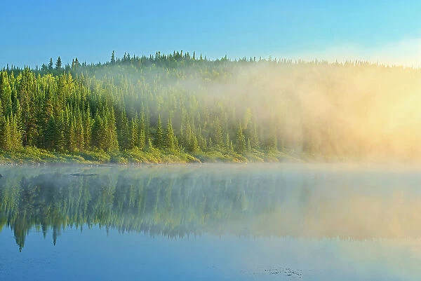 Northern lake in fog at sunrise Chibougameau, Quebec, Canada