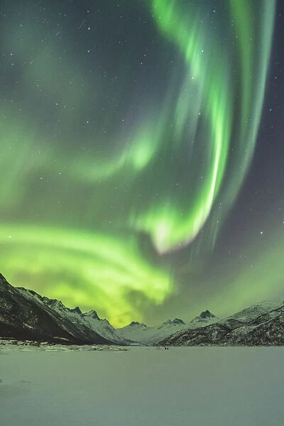 Northern lights with mountains and two people in winter. Kleppstad, Nordland county