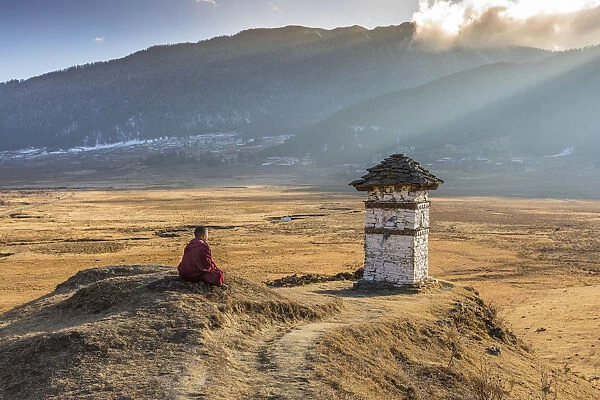 Novice Monk (Child Monk) praying in front of a stupa in Phobjikha Valley, Bhutan