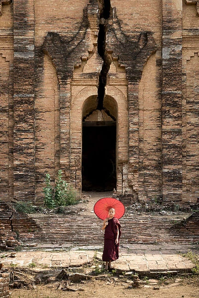 Novice monk standing in front of the unfinished Pahtodawgyi pagoda known for a crack