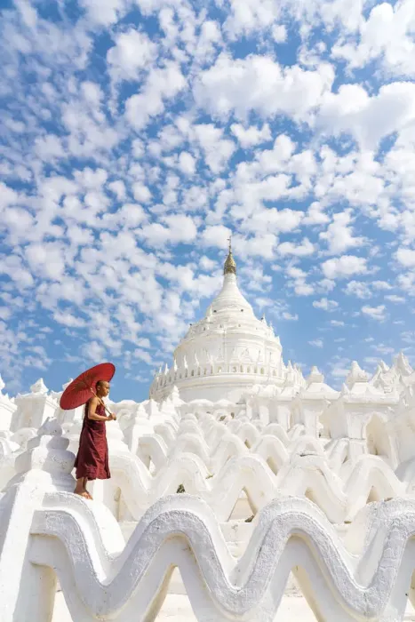 Framed Print : Novice monk with an umbrella standing at white Hsinbyume pagoda