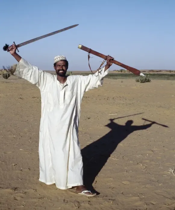 Framed Print : A Nubian man displays his sword at an oasis in Framed Print : A Nubian man displays his sword at an oasis in