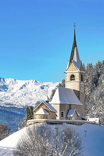 Old bell tower and church with snowcapped mountains on background, Alvaneu, Davos, Graubunden canton, Switzerland