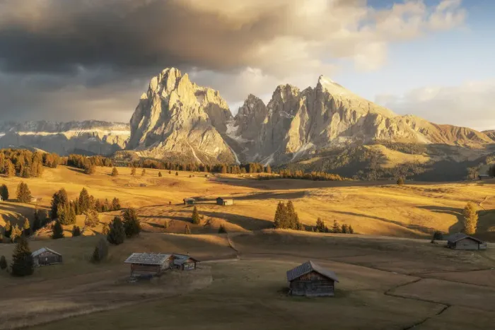 Framed Print : Some old cabins lost in the meadows of the Alpe di Siusi (Seiser Alm) during an early autumn sunset, with the Sassolungo and Sassopiatto in the background. Dolomites, Italy
