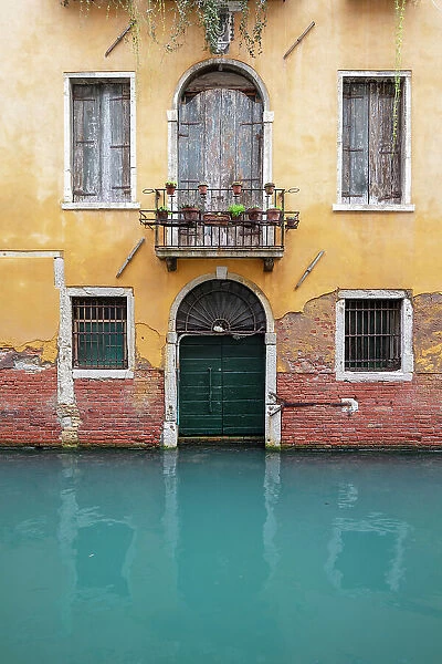 An old facade reflected in a canal, Venice, Italy