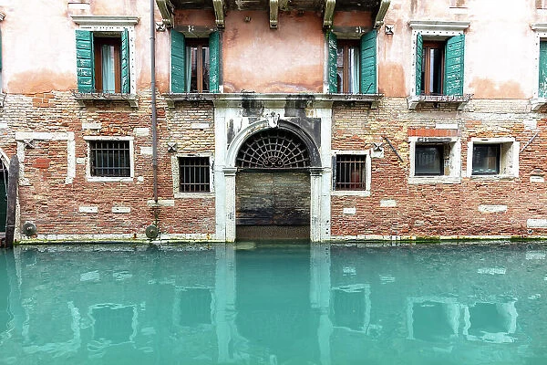 An old facade reflected in a canal, Venice, Italy