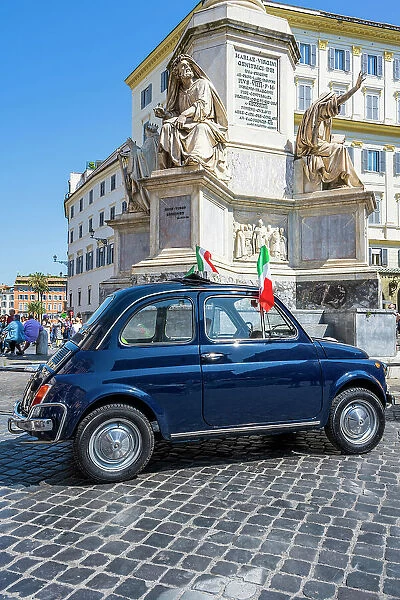 Old iconic blue Fiat 500 car with Italian flags parked in a cobbled square, Rome, Lazio, Italy