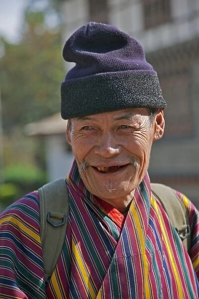 An old man at Trashigang wearing the traditional gho robe of all Bhutanese men