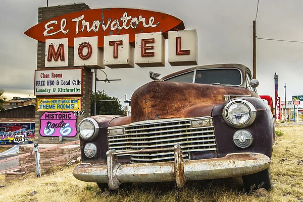 Old rusted Pontiac car and vintage motel sign behind along the historic U. S. Route 66