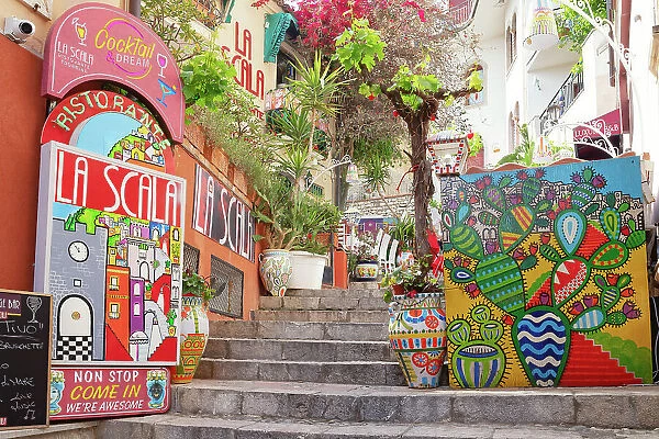 Old town street filled with billboards and artwork, Taormina, Sicily, Italy