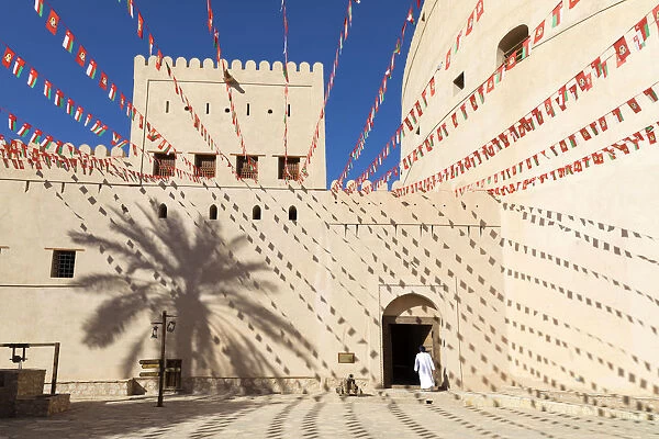 An Omani man walks into Bahla Fort decorated to celebrate the birthday of Sultan Qaboos