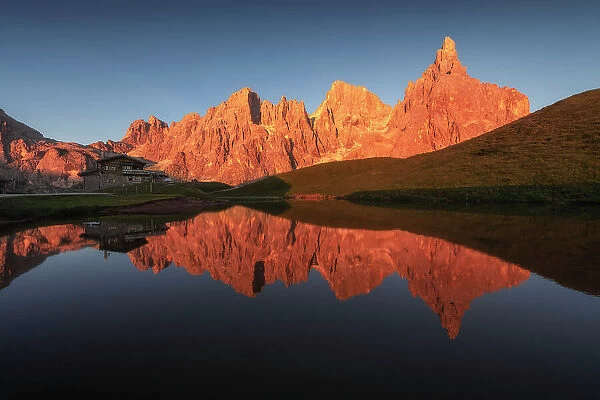The Pale di San Martino lit up at sunset during a summer evening, reflecting in the pond of the Baita Segantini. Dolomites, Italy