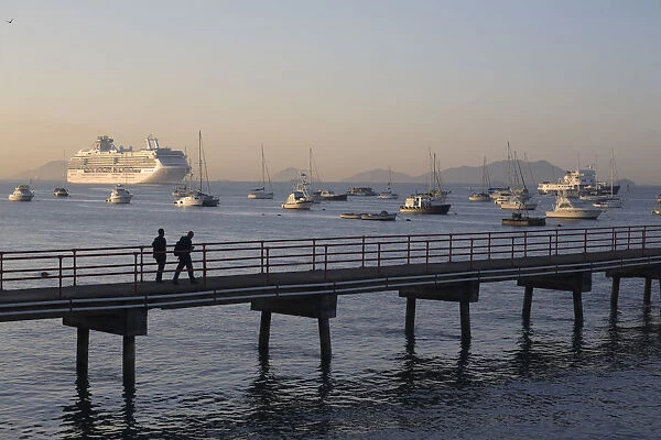Panama, Panama City, People walking along jetty with a Cruise ship sailing in The