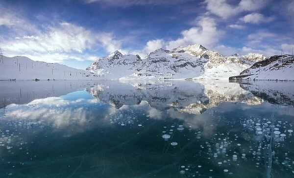 Panorama of ice bubbles and frozen surface of Lago Bianco at dawn Bernina Pass canton