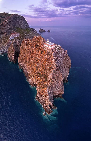 Panoramic aerial view of the lighthouse on top of a rocky cliff at dusk, Punta della Guardia, Ponza island, Pontine archipelago, Latium region, Italy
