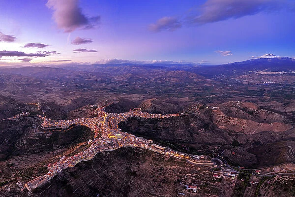Panoramic aerial view of the man-shaped (or star-shaped) illuminated village of Centuripe with Etna volcano, Centuripe, Enna province, Sicily, Italy
