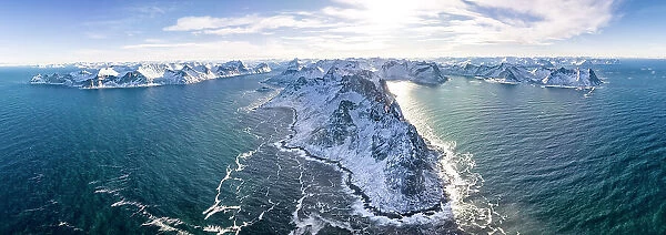 Panoramic aerial view of waves crashing on snowy mountains, Mefjorden, Senja, Troms county, Norway