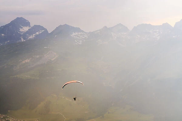 Paraglide flying in the mist over mountains of upper Engadine Graubunden, Switzerland