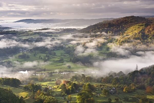 Patches of morning mist float above countryside near the River Brathay, Lake District National Park