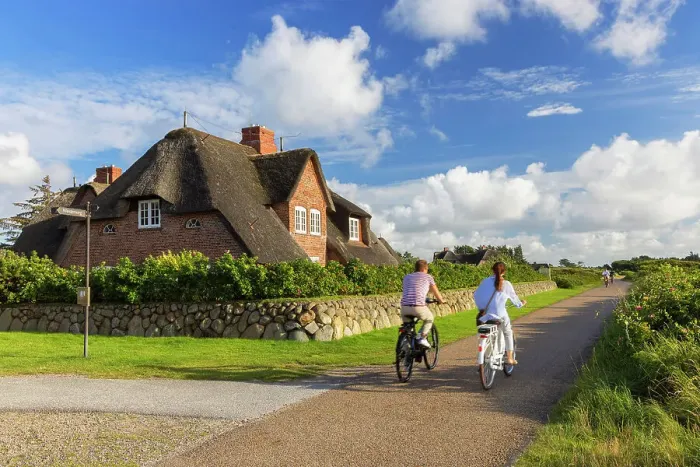 Framed Print : People cycling past traditional thatched house, Kampen, Sylt, Schleswig Holstein, Germany Framed Print : People cycling past traditional thatched house, Kampen, Sylt, Schleswig Holstein, Germany