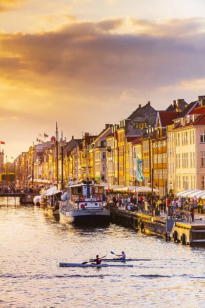 Two people kayaking in the Nyhavn canal in Copenhagen at sunset, Denmark