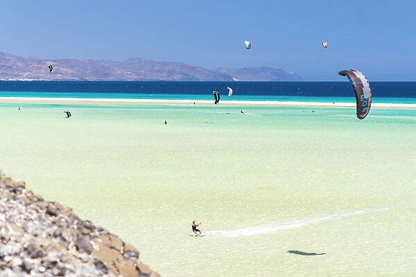 People riding the ocean waves with kiteboard at Sotavento beach, Jandia, Fuerteventura