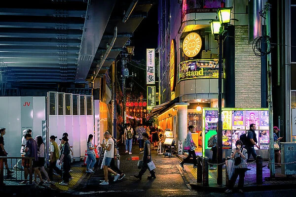 People walk on the streets in summer night in Tokyo under illuminated signs