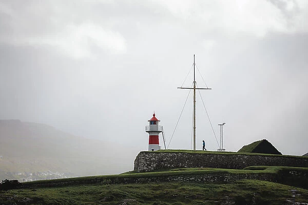 A person walking towards Skansin lighthouse in Torshavn. Faroe Islands
