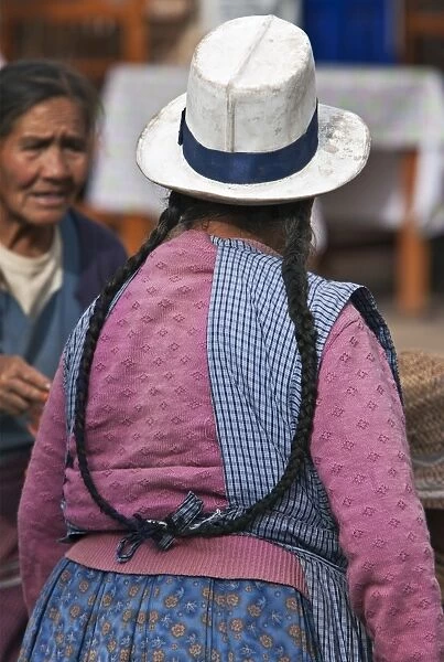 Peru. An Indian woman with long pigtails at Pisacs busy Sunday market