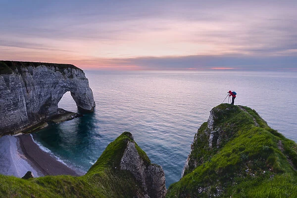 The photographer over the cliff in Etretat at sunset in Normandy, France, Europe