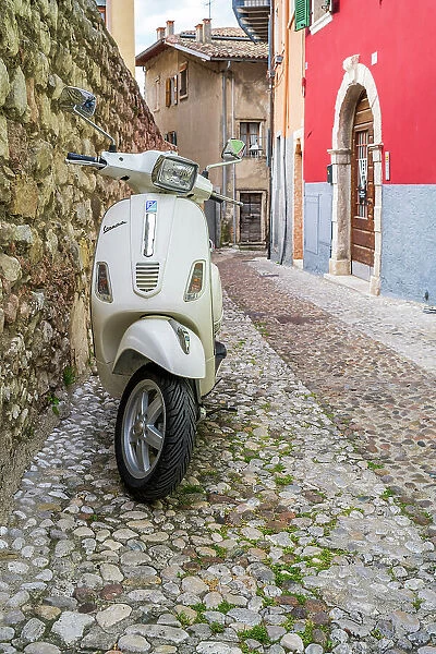 Piaggio Vespa scooter parked in a cobbled street of Malcesine, Lake Garda, Veneto, Italy