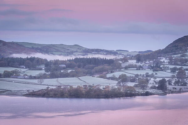 Pink dawn sky above frost covered countryside on the shores of Crummock Water in the Lake