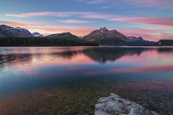 Pink sky at dawn illuminates the peaks reflected in Lake Sils Engadine Canton of