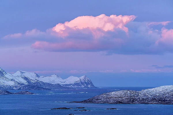 Pink sunrise over the cold arctic sea and snowy mountains of Senja island, Troms county, Norway