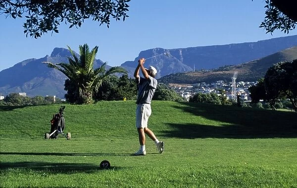 A player tees off at the golf course at Green Point overlooked by Table Mountain