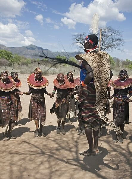 A Pokot warrior wearing a cheetah skin jumps high in the air surrounded by young women to celebrate an Atelo ceremony. The Pokot are pastoralists speaking a Southern