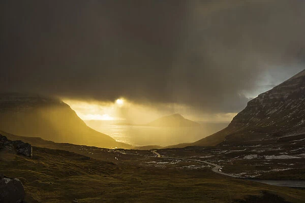 Rain illuminated by sun above the village of Norðradalur. In the background the island of Koltur. Streymoy, Faroe Islands