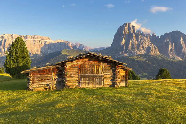 Last rays of sun on traditional hut with view on Sassolungo and Sella Group