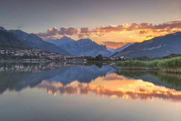 Red clouds and Lecco mountains reflected on lake Annone, Lecco province, Brianza