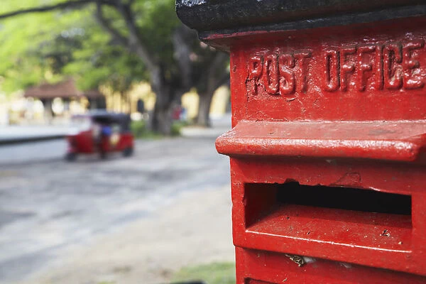 Red post box with tuk tuk in background, Galle, Sri Lanka