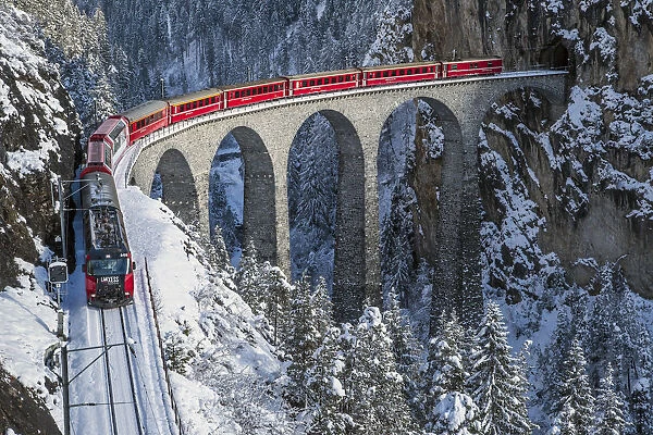 Red train going on the Landwasser Viadukt in winter. Filisur, Canton of graubunden