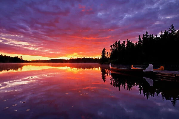 Reflection of clouds in Lac du Fou at sunrise with canoes La Mauricie National Park, Quebec, Canada