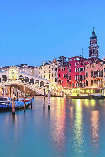 Rialto Bridge over the Grand Canal and historic buildings lit by street lanterns at dusk, Venice, Veneto, Italy