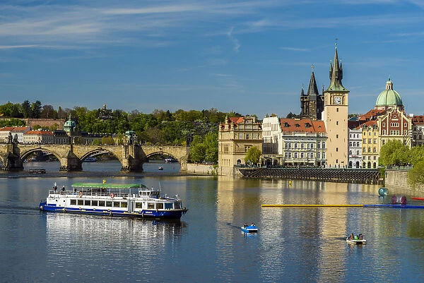 River cruise boat on Vltava River with Smetana Museum and Charles Bridge in the background
