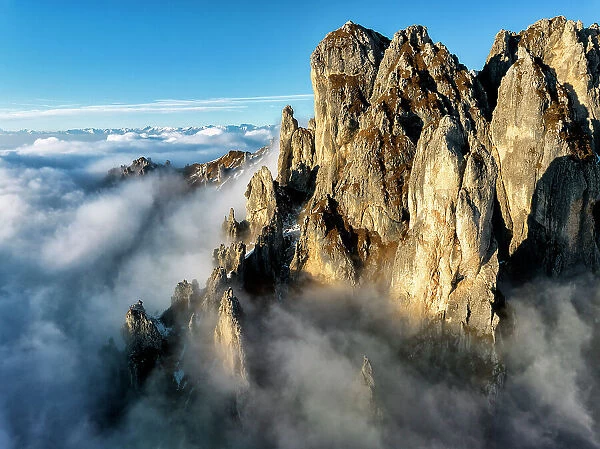 The rock towers of the southern Grigna emerge from the clouds. Grignetta, Grigne group, Lake Como, Italy