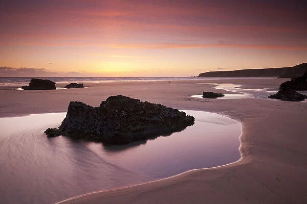 Rockpools on the sandy shores of Bedruthan Steps at sunset Cornwall, England. Spring