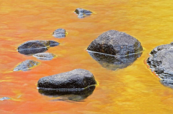 Rocks in Dryberry Creek with autumn colored reflections of trees Sioux Narrows, Ontario, Canada