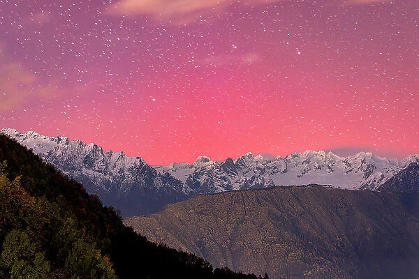 Romantic pink and purple night sky during the Aurora Borealis over the Italian Alps, Val Masino, Valtellina, Lombardy, Italy