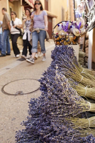 Rousillion; France. People walking down a street with lavender for sale in the foreground