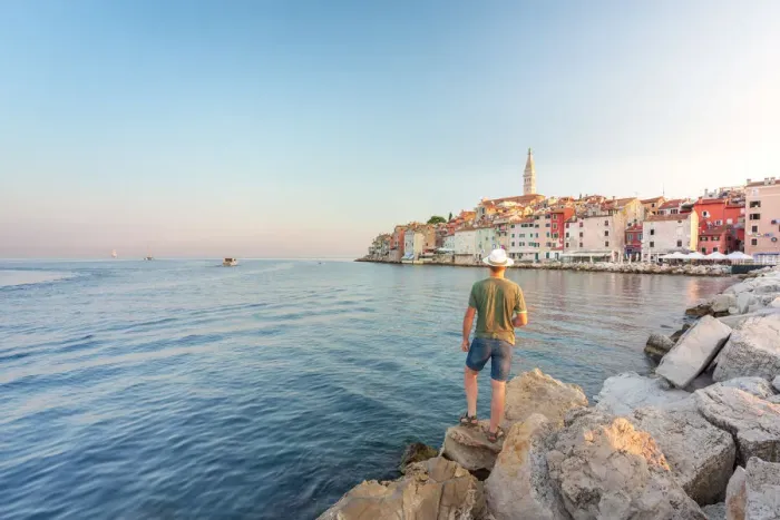 Framed Print : Rovinj - Rovigno, tourist on the rocks of the pier admires the splendid old town, Istria